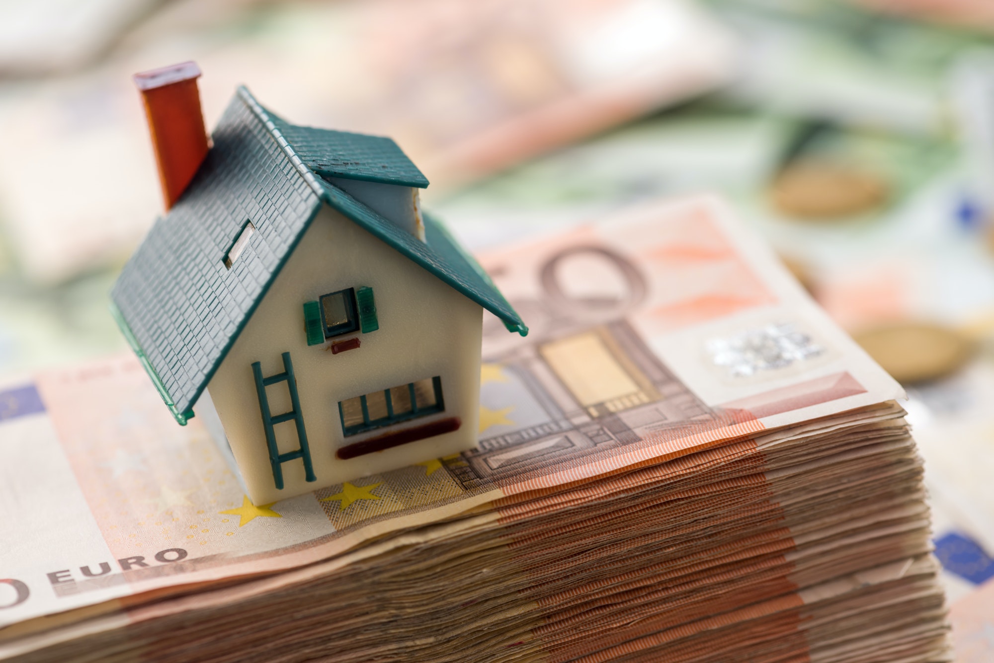 small toy-house on top of stack of cash